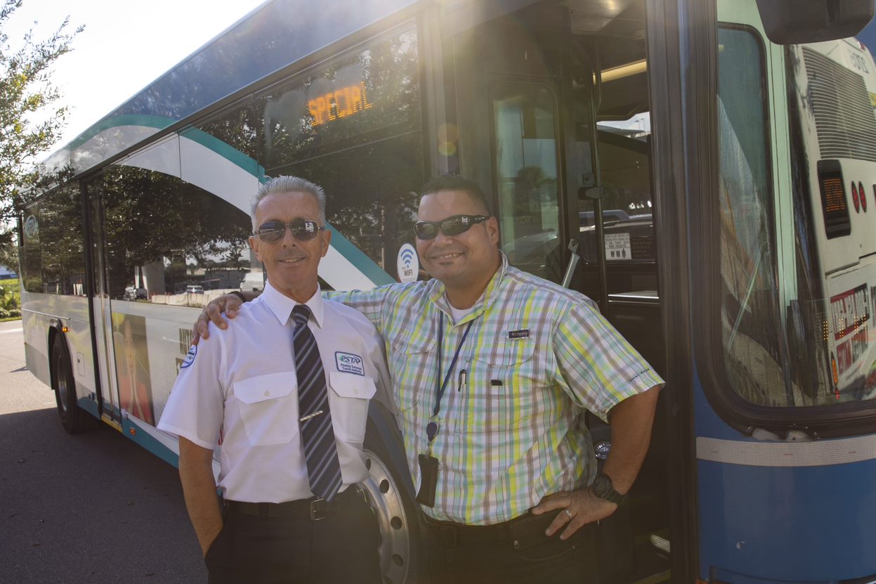 A bus operator and trainer stand in front of a PSTA bus