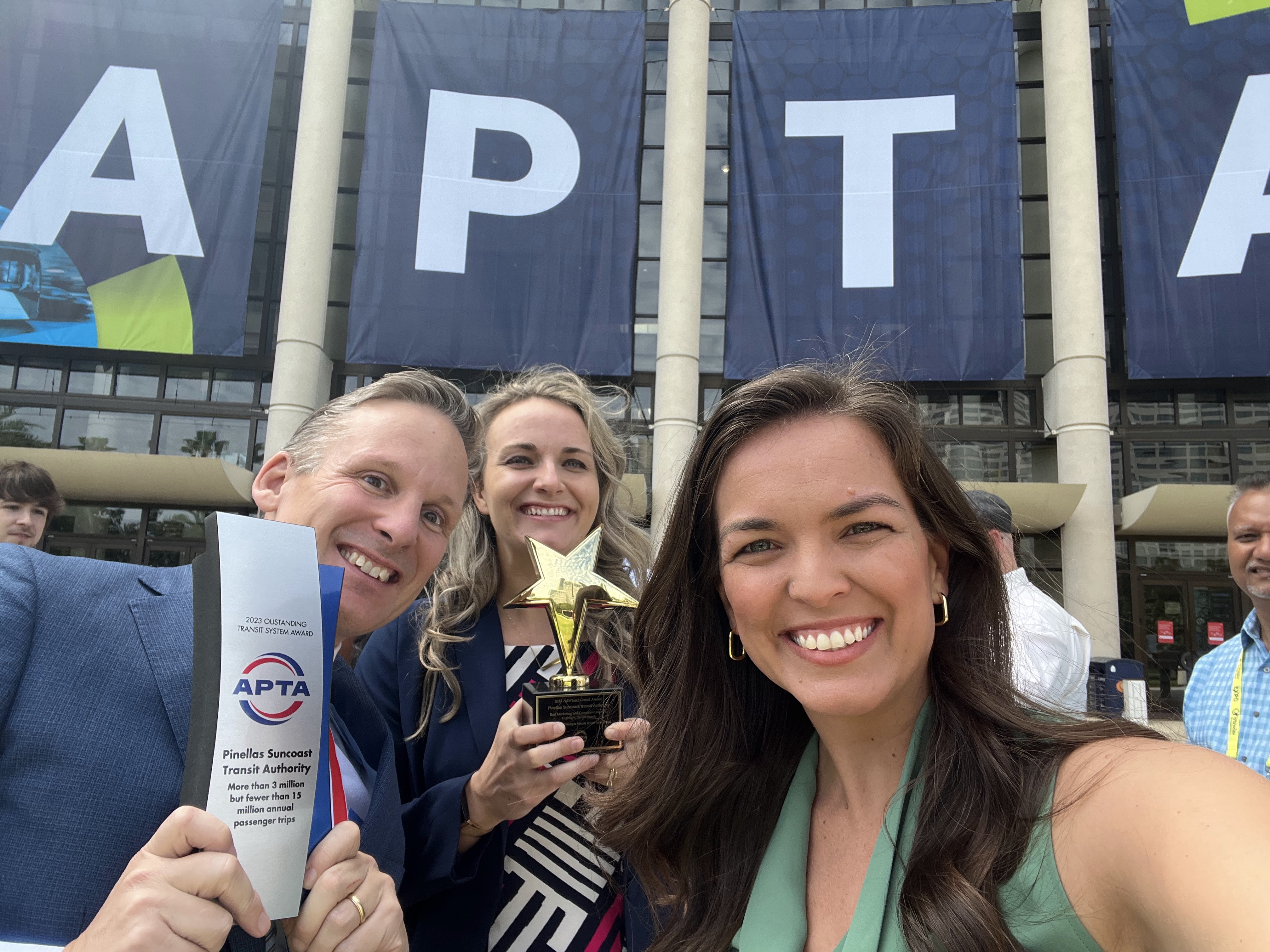 CEO Brad Miller, Communications Manager Stephanie Weaver, and Marketing Director Whitney Fox smiling while holding awards outside of the APTA conference