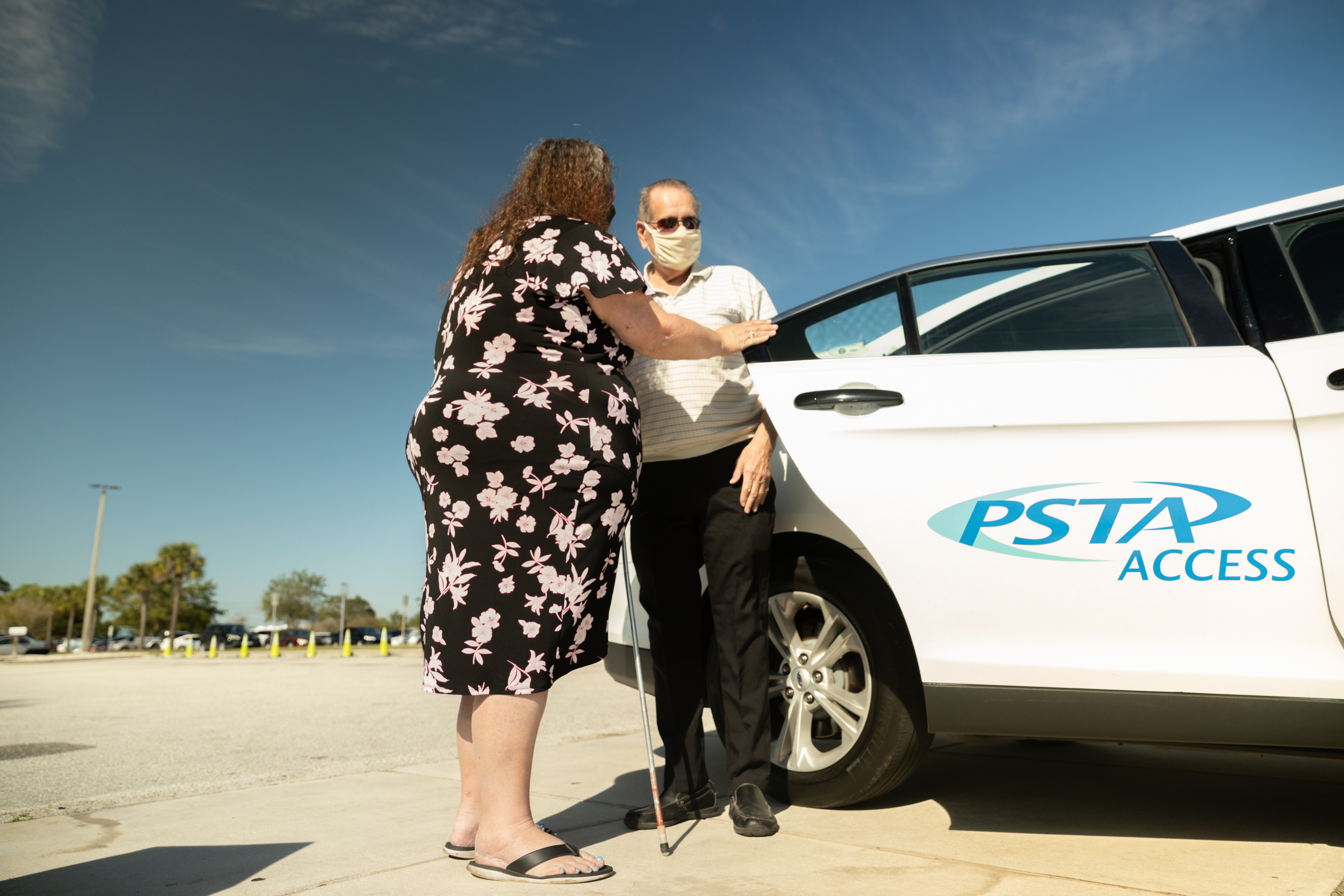 A hard of seeing man being guided into a PSTA Access paratransit car.