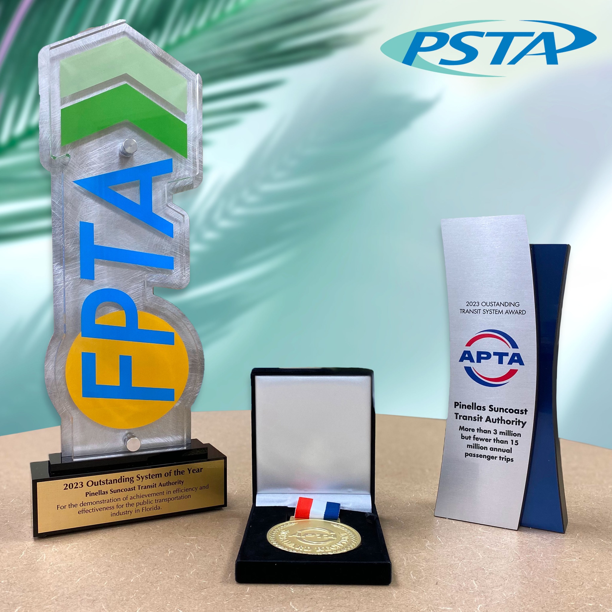 A photo of two trophies and a medal. These awards represent PSTA winning best transit system in the state and the nation for 2023.