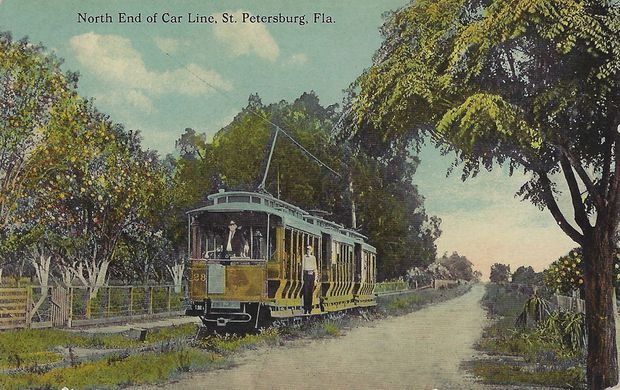 An old colorized postcard showing a yellow trolley passing orange groves in the Southside section of St. Petersburg.