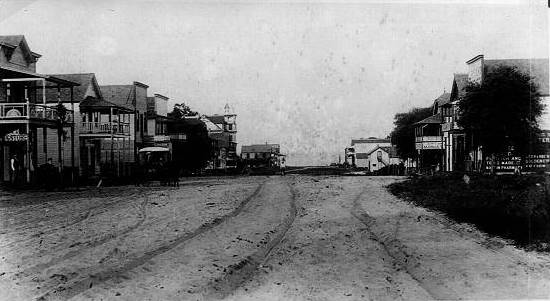 A black and white image of Central Avenue in 1895, before roads or tracks were laid. There's only a wide dirt road with horse-drawn wagon tracks in the dirt.