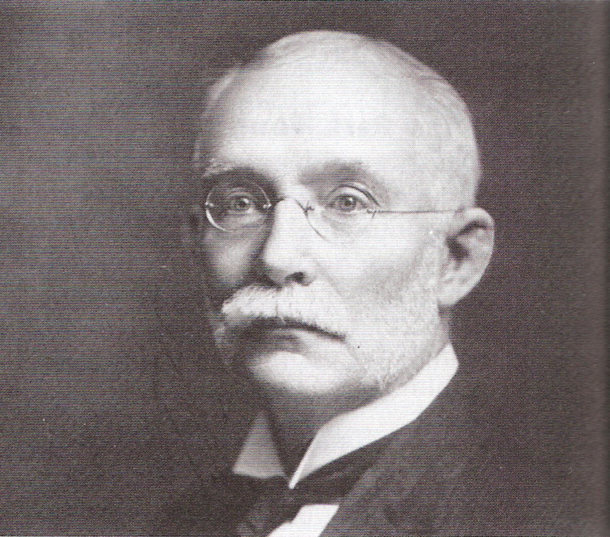 A black and white photo of Frank Allston Davis around the early 1900s. He is middle-aged with thin wireframe glasses, white mustache and beard, and receding white hair.