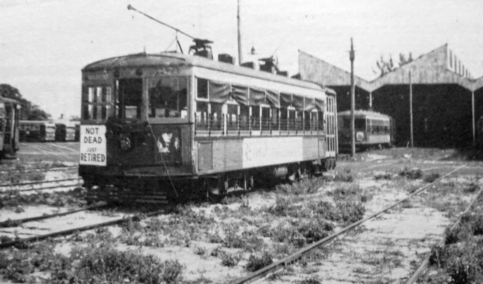 A black and white photo of the last trolley with the sign "Not dead, just retired"