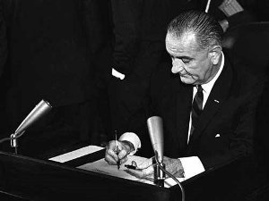 A black and white photo of President Lyndon B. Johnson signing the Urban Mass Transportation Act of 1964.