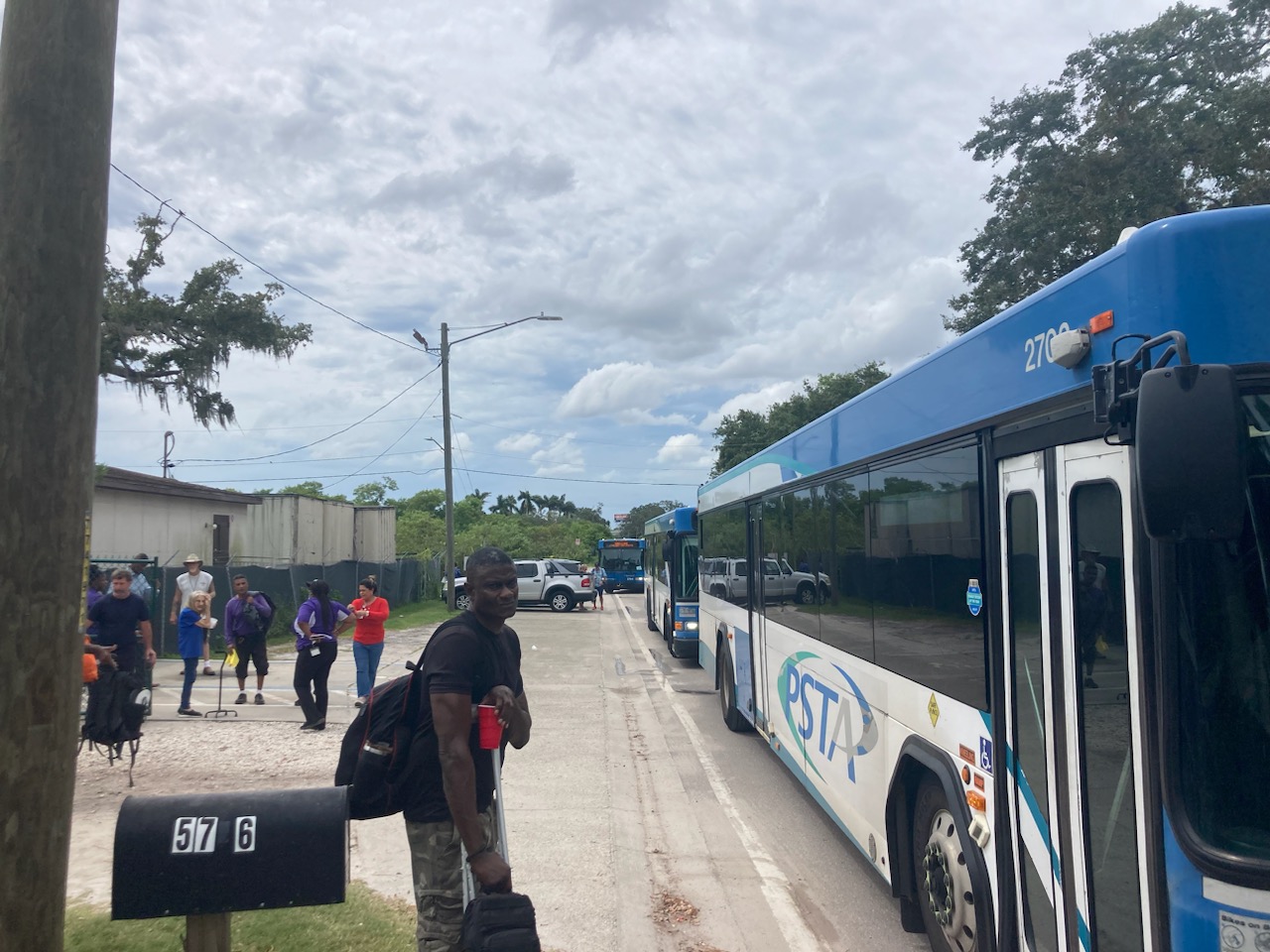 Hurricane evacuees prepare to board a line of older PSTA diesel buses that will transport people to storm shelters.