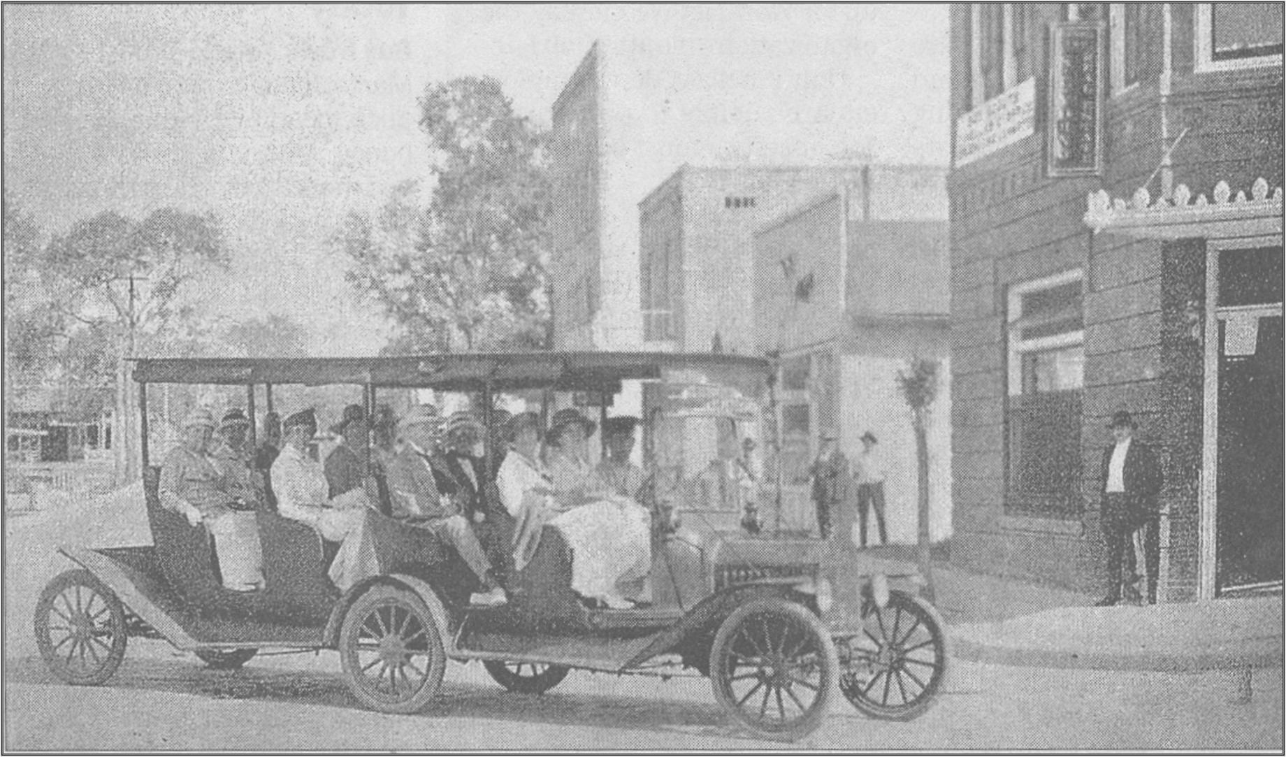 A black and white photograph of the first commercially operated bus in Pinellas County. The bus is two Ford Model T automobiles welded together. The bus is turning the corner of a street in 1919.