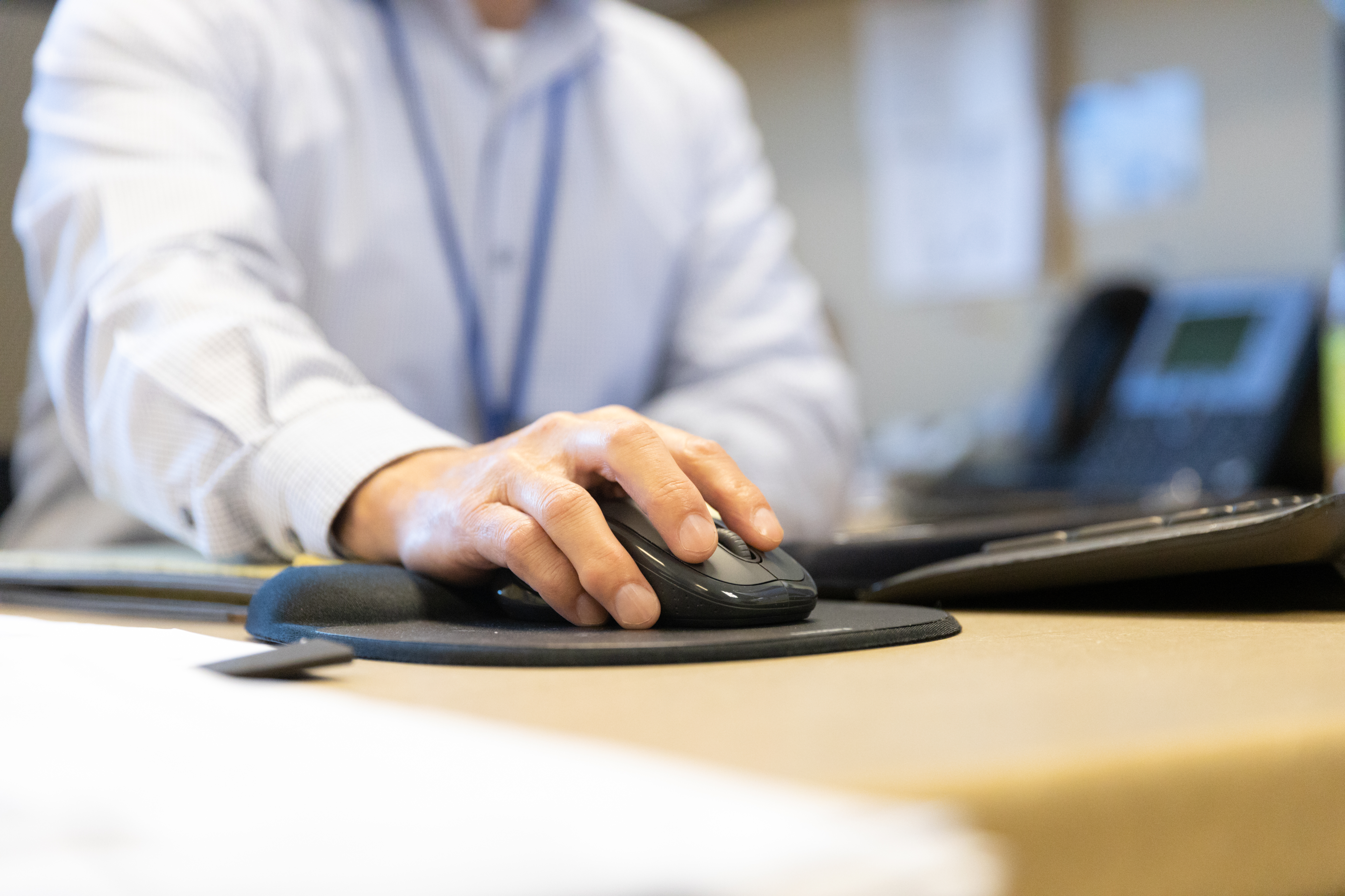 A photo of a person's hand on their mouse at their desk at PSTA.