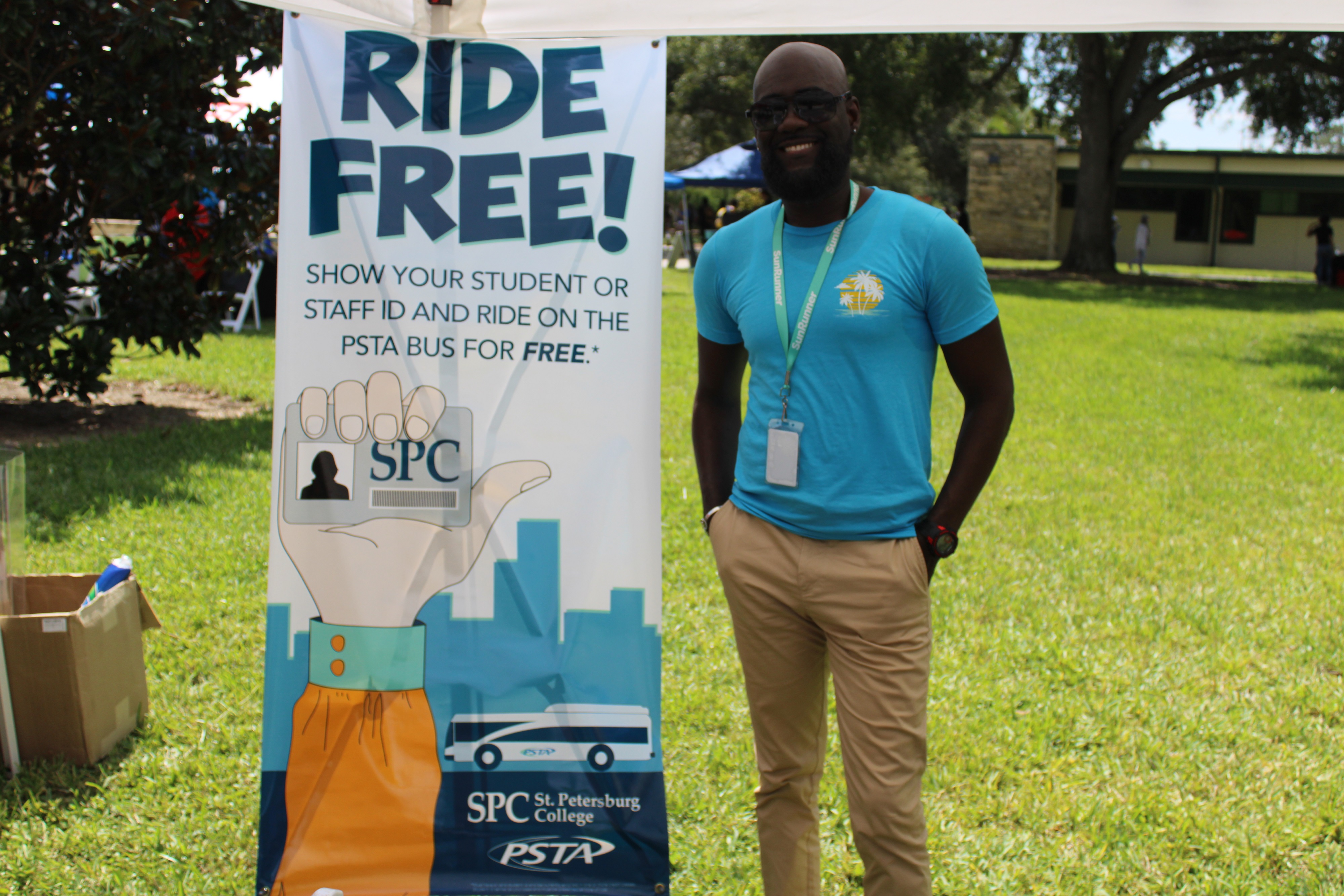 Business Partnership Specialist Marvin “Joe” Joseph stands next to a tall banner that reads "Ride Free! Show your student or staff ID and ride on the PSTA bus for free"