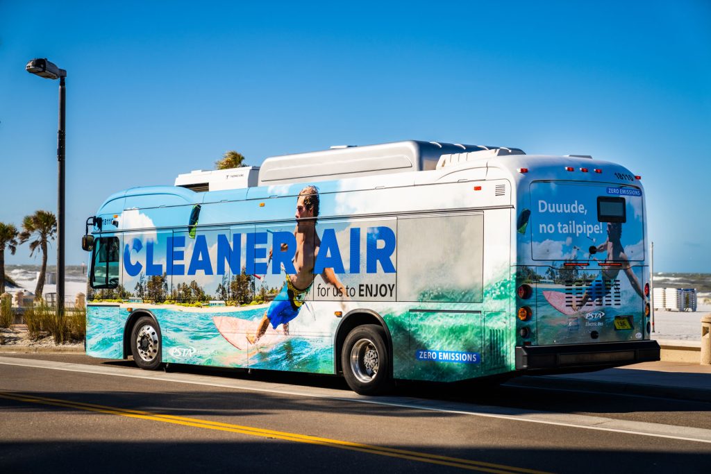A photo of PSTA's first electric bus, which says "Cleaner Air for us to ENJOY" on the side.