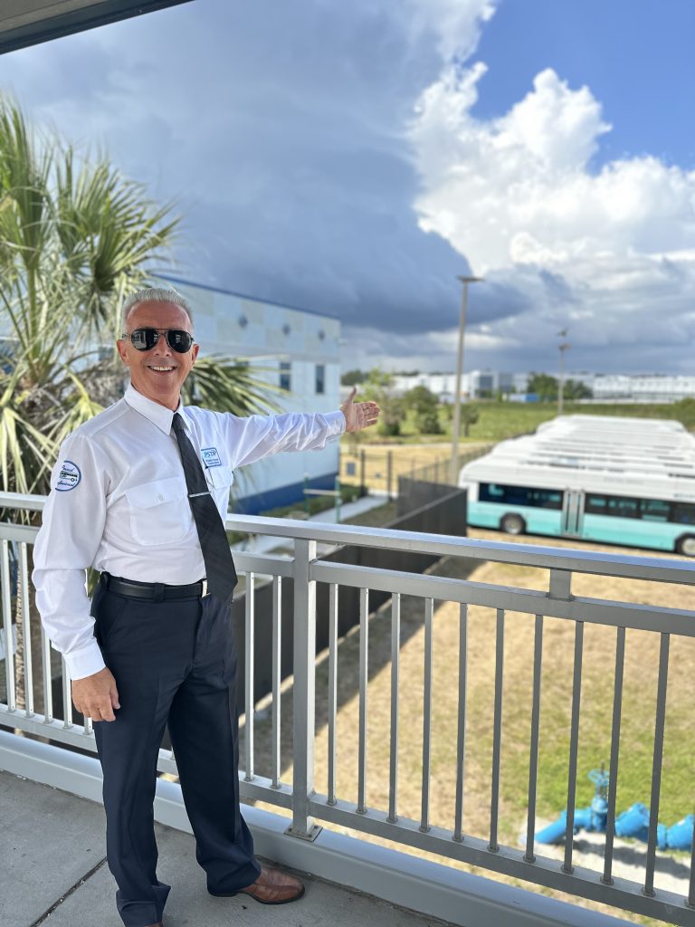 Milan standing infront of railing showing bus fleet
