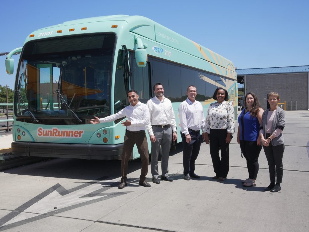 six employees next to SunRunner bus in bus yard