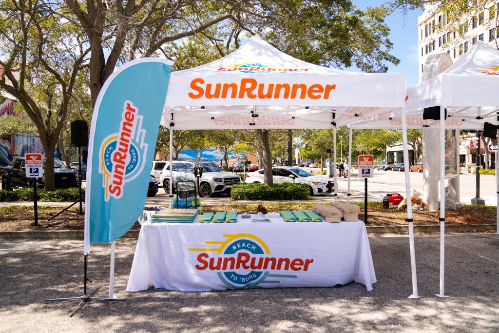 A photo of a SunRunner tent and table with SunRunner promo items to do community outreach and tell people about the new service.