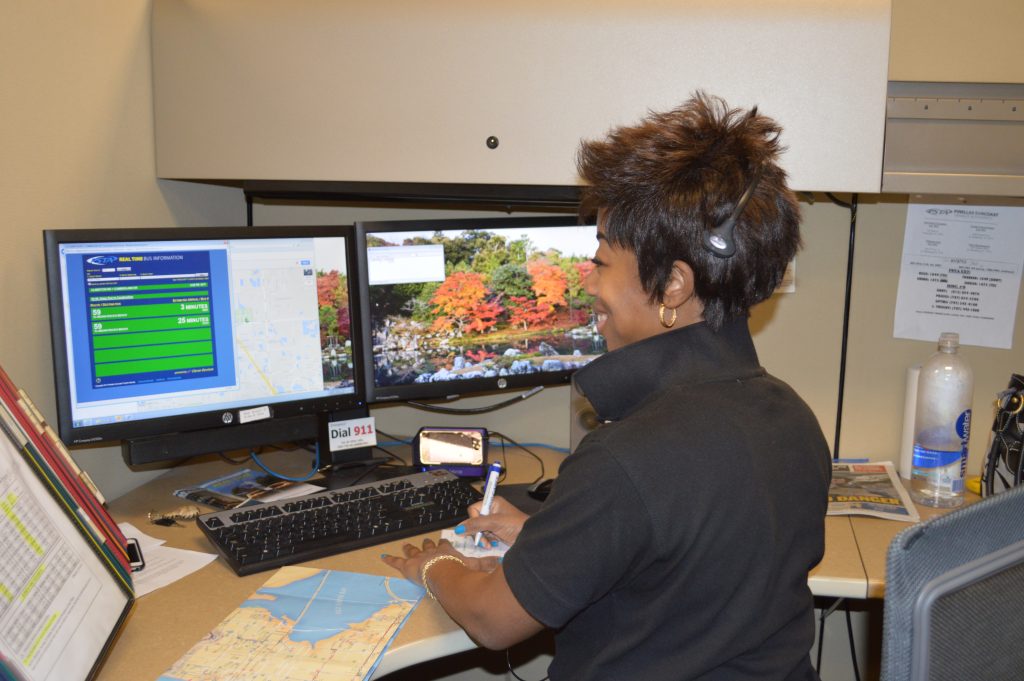 A CSR sitting at a computer looking of route information for a caller while she takes notes.