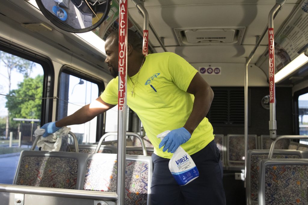 A man in a bright yellow PSTA shirt cleans and sanitizes the interior of a bus before it hits the road.