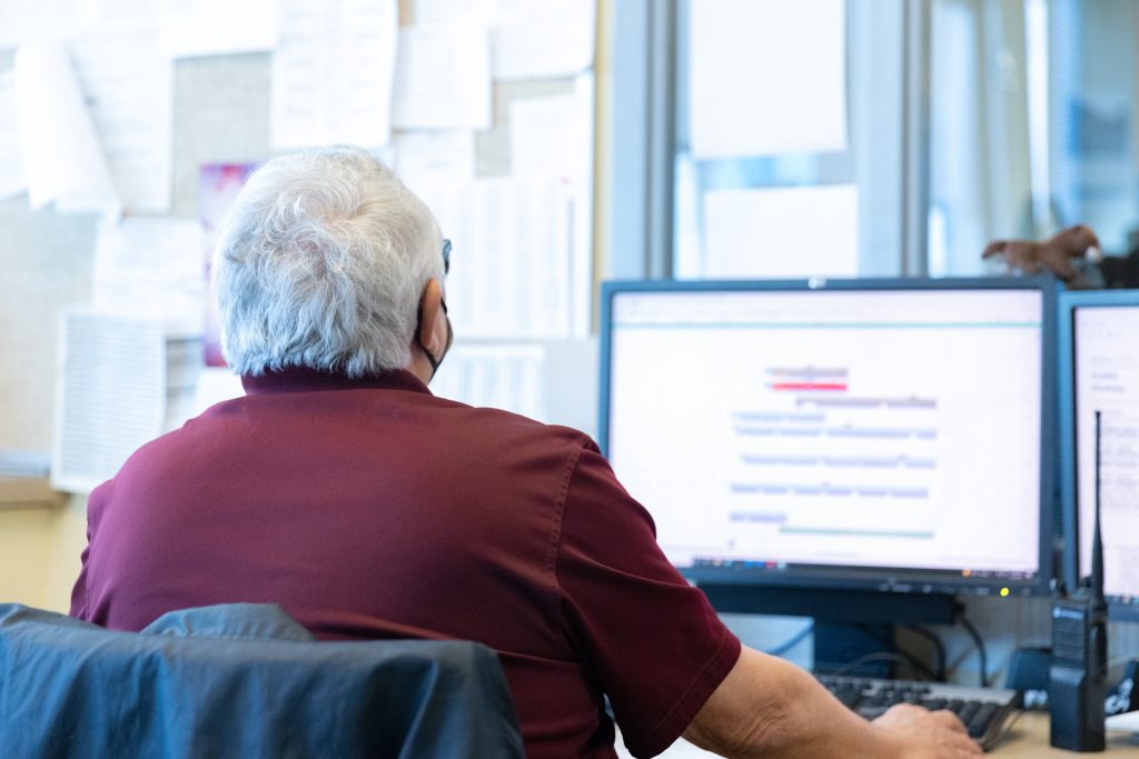 A photo of a transportation supervisor reviewing a schedule on his computer.