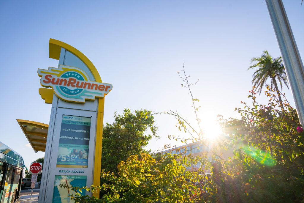 A photo of a SunRunner station and totem with the sun shining behind it.